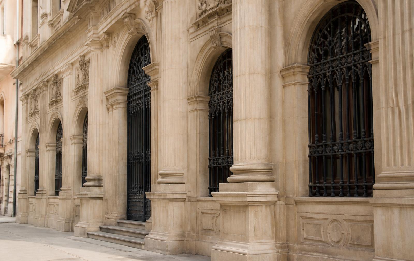 Fachada de piedra de un edificio institucional con arcos y columnas clásicas
